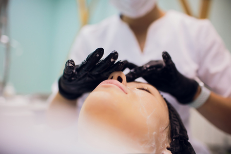 Wipe with sterile napkin face. Young woman receiving treatments in beauty salons.の写真素材