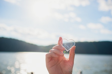 Silhouette of a girl making a heart-shape in nature.