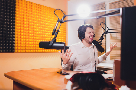 Portrait of radio host using sound mixer on table in studio.の写真素材