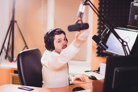 Portrait of radio host using sound mixer on table in studio.の写真素材