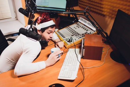 Young businessman employee drinking in the office at desk. new year hatの写真素材