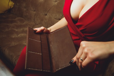 large breasts, cutout on dress, red color of clothes, woman holds clutch or purse