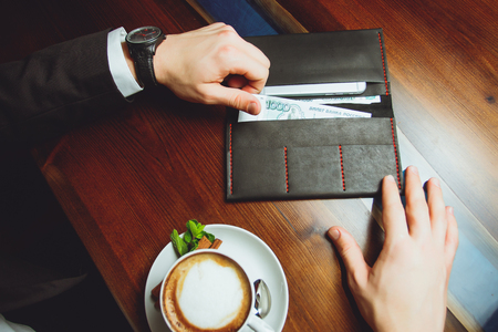 Hands take out russian rubles from wallet. Closeup on a man's hands as he is getting a banknote out of his walletの写真素材