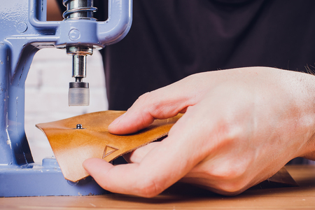 leather craftsman working making products at table in workshop studio
