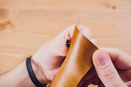 leather craftsman working making products at table in workshop studio