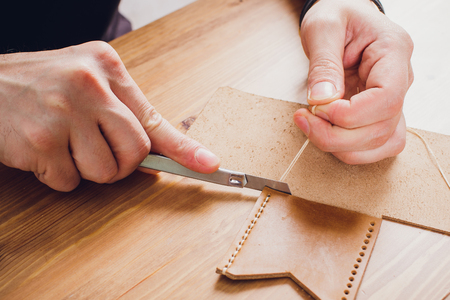 leather craftsman working making products at table in workshop studioの写真素材
