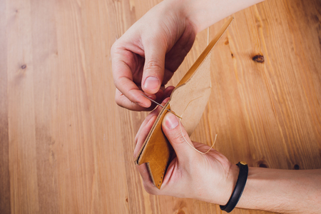 leather craftsman working making products at table in workshop studio