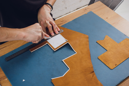 leather craftsman working making products at table in workshop studio