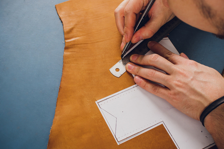 leather craftsman working making products at table in workshop studioの写真素材