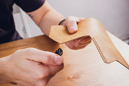 leather craftsman working making products at table in workshop studioの写真素材