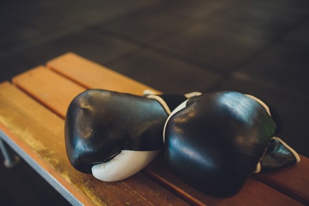 Two black Boxing gloves lie on the Boxing ring in white. The shadow of the ring falls on the floorsの写真素材