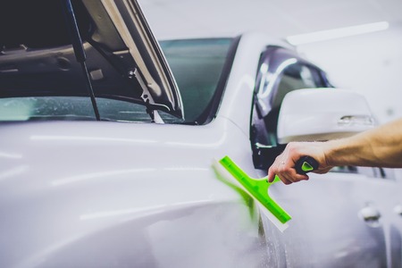 Car wrapping specialist putting vinyl foil or film on car.