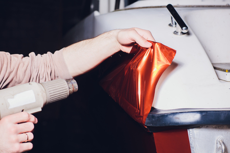 Car wrapping specialist putting vinyl foil or film on car. Selective focus.の写真素材