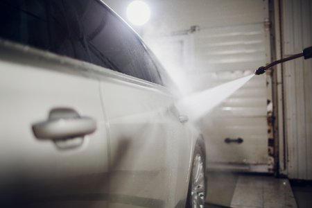 man washing automobile at manual car washing self service,cleaning with foam,pressured water.Transportation care concept.Washing car in self service station with high pressure blasterの写真素材