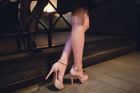 Close-up of young woman's legs in high-heeled black shoes isolatedの写真素材