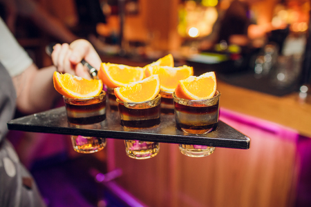 Several shot glasses on silver tray in bar setting.の写真素材