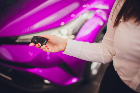 Female holding car keys with car on background.の写真素材