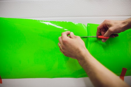 Car wrapping specialists wrapping a vehicle with grey vinyl film or foil