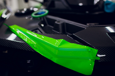 Car wrapping specialists wrapping a vehicle with grey vinyl film or foilの写真素材