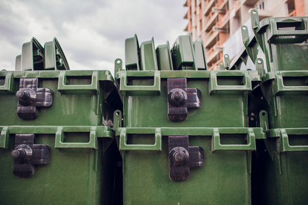 Six new plastic green garbage standard containers. Back side of the city sports festival. In the background - trading canvas tentsの写真素材