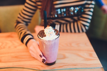 Girl holding milkshake with donuts and other sweets in jarの写真素材