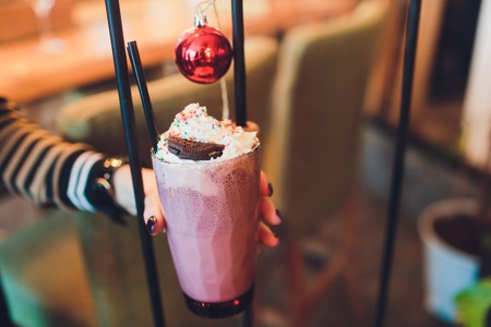 Girl holding milkshake with donuts and other sweets in jarの写真素材