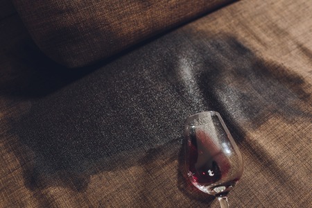 Red wine spilled on a grey couch sofaの写真素材