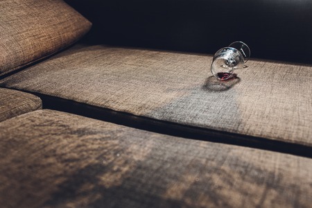 Red wine spilled on a grey couch sofaの写真素材