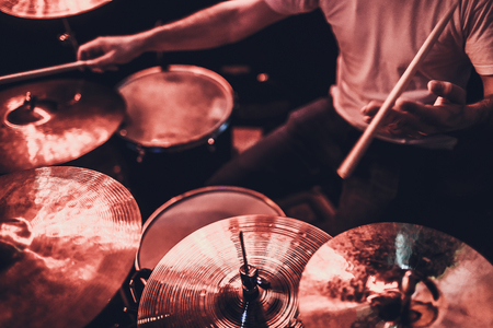 music, people, musical instruments and entertainment concept - male musician or drummer playing drum kit at studio over holidays lights backgroundの写真素材