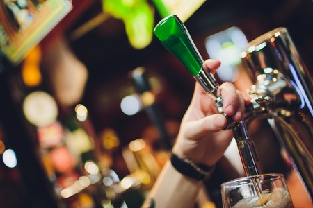 Barman hands pouring a lager beer in a glassの写真素材