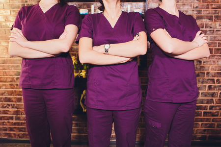 Portrait of female brunette cosmetologist in uniform in the cosmetology office three young women.の写真素材