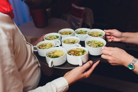 Close up of waiter serving food in a restaurant. Soft focus.