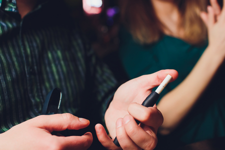 IQOS heat-not-burn tobacco product technology. Man holding e-cigarette in his hand before smoking.の写真素材
