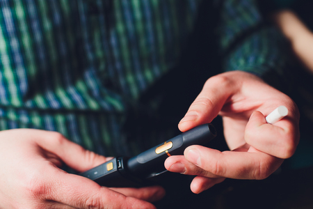 IQOS heat-not-burn tobacco product technology. Man holding e-cigarette in his hand before smoking.の写真素材