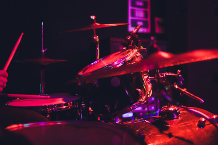 Drummer with a drumsticks in his hands playing on drum set on stage on the black background.の写真素材