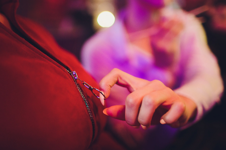 the girl's hand fastens the zipper on the jacket outdoor. woman's hand fastens the zipper on the coat closeupの写真素材
