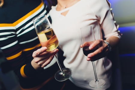 Glass of wine in beautiful female hands. Large glass filled with red wine in woman manicured hands. Concept of romance and celebrationの写真素材