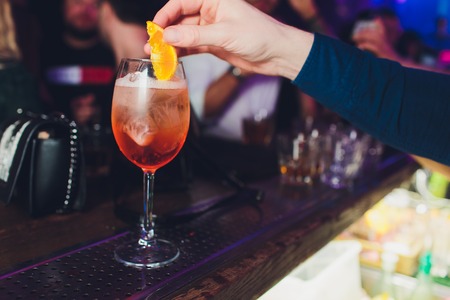 Barman making cocktail with sparkling wine, Aperol and orange. Close up view focused on handsの写真素材