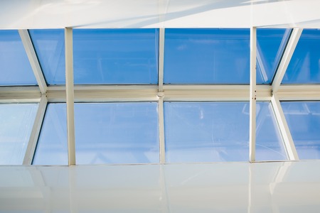 A modern open skylight mansard window in an attic room against blue sky