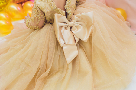 The small dress and shoes for baby stand on the bed goldの写真素材