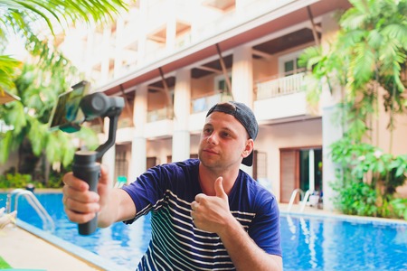 Young male video blogger creates video content for his channel. Video shots for users while sitting...