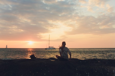 Enjoying vacation. Young traveling woman enjoying sunset on sea view point.の写真素材