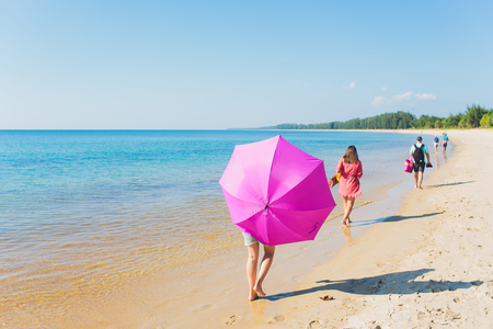 Girl with an orange umbrella on the sandy beach.の写真素材
