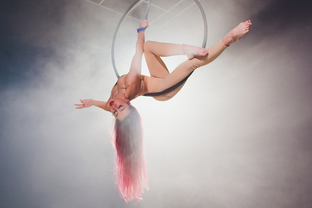 Aerial acrobat in the ring. A young girl performs the acrobatic elements in the air ring.の写真素材