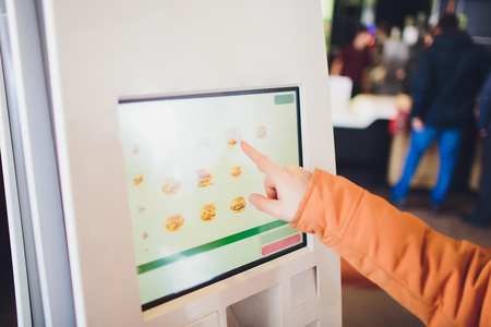 A man orders food in the touch screen terminal with electronic menu in fast food restaurant.の写真素材