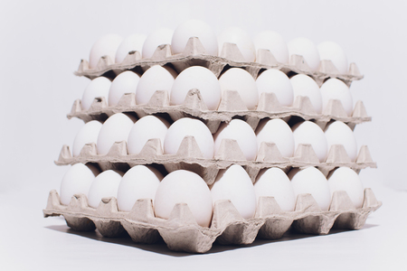 White eggs of a hen in harmless, cardboard packing on a white background. 5 packs.の写真素材