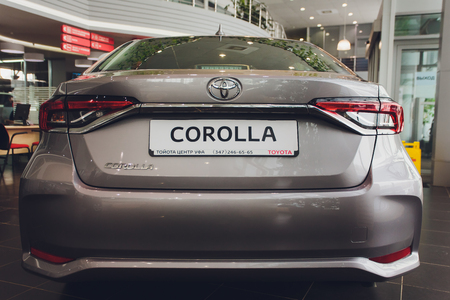 Ufa, Russia - 14 February 2019.All-new Toyota Corolla arrived to dealership. Black gloss car with dealers license plate standing next to showroom under Toyota emblem.のeditorial素材