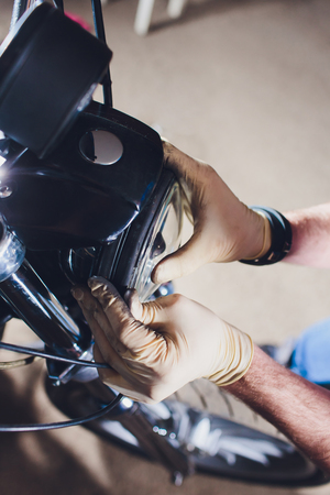 Man fixing bike. Confident young man repairing motorcycle near his garage. replacement lamp in the headlampの写真素材