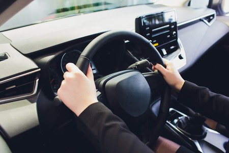 Woman driving a car, hands on steering wheel close-up.の写真素材