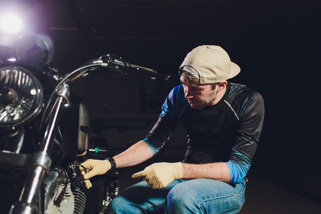 Man fixing bike. Confident young man repairing motorcycle near his garage.の写真素材